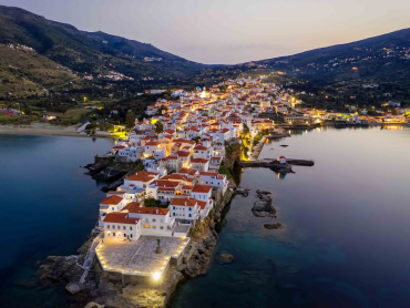 Aerial view over the beautiful illuminated town of Andros island, Cyclades, Greece, during dusk time